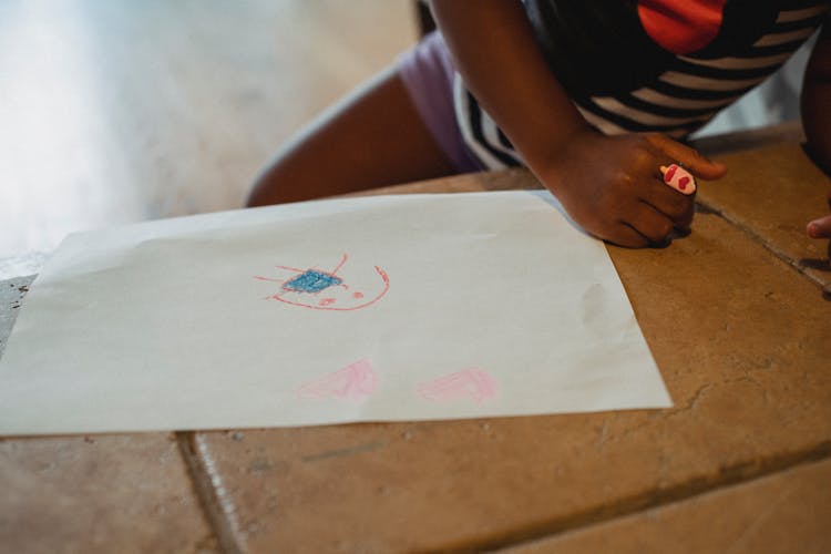 Crop Unrecognizable Black Child Leaning On Stone Bench With Drawing