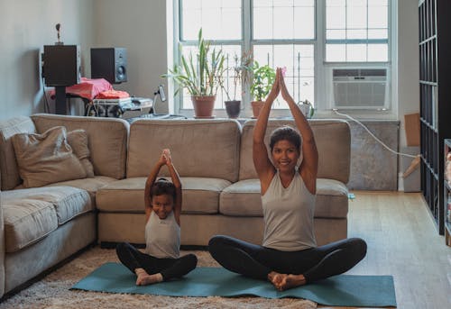 Happy mother and daughter stretching together at home