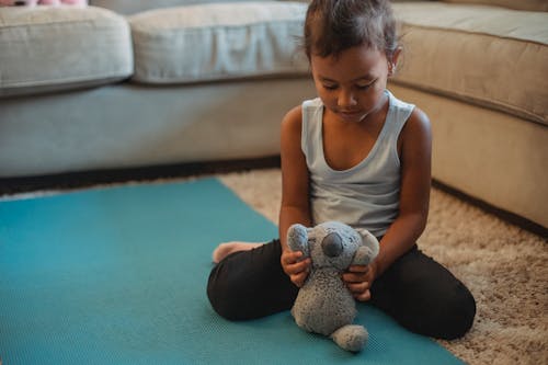 Focused Hispanic girl in activewear playing with toy on floor and looking down