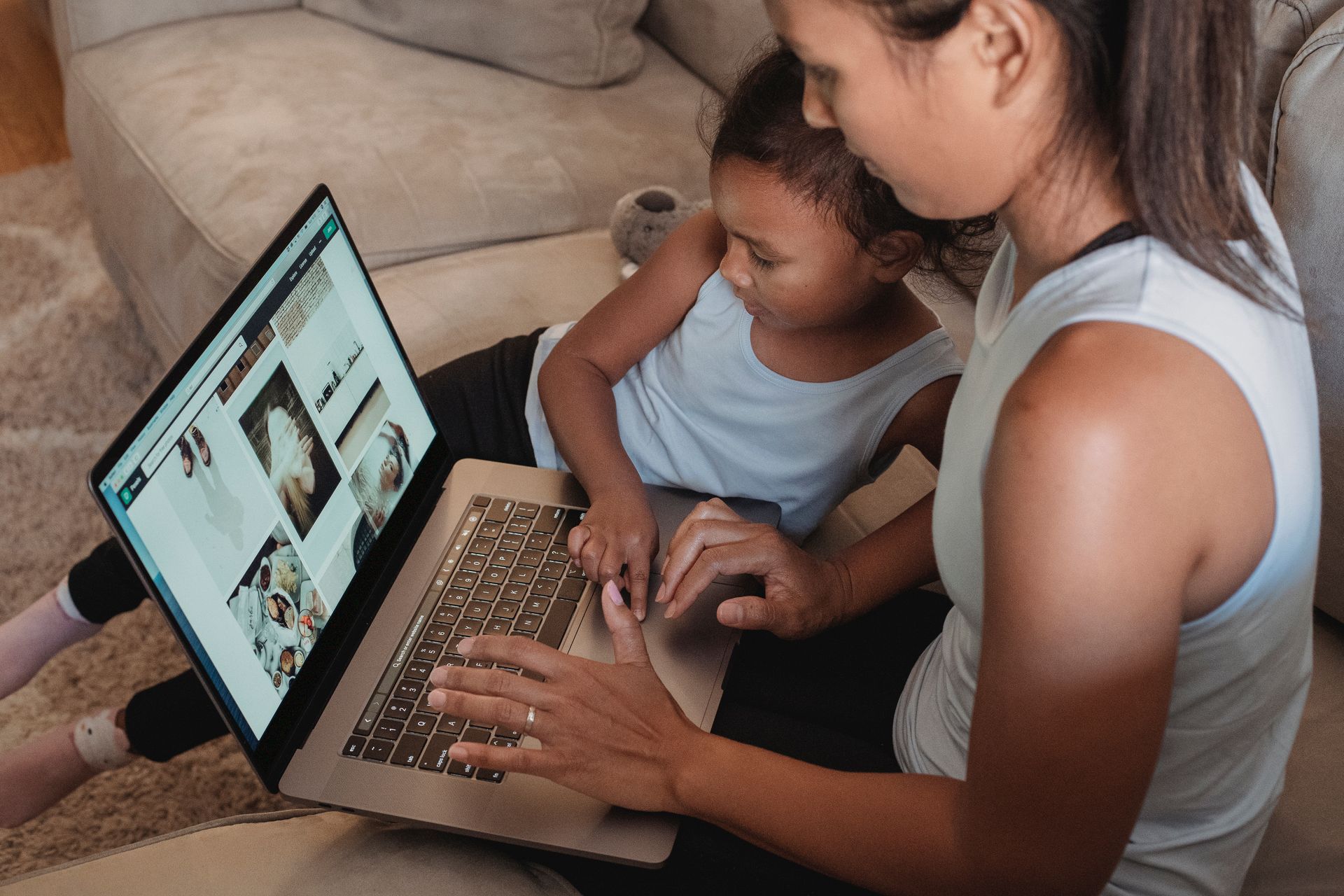 Mother and daughter exploring online content together on a laptop in a cozy living room setting.