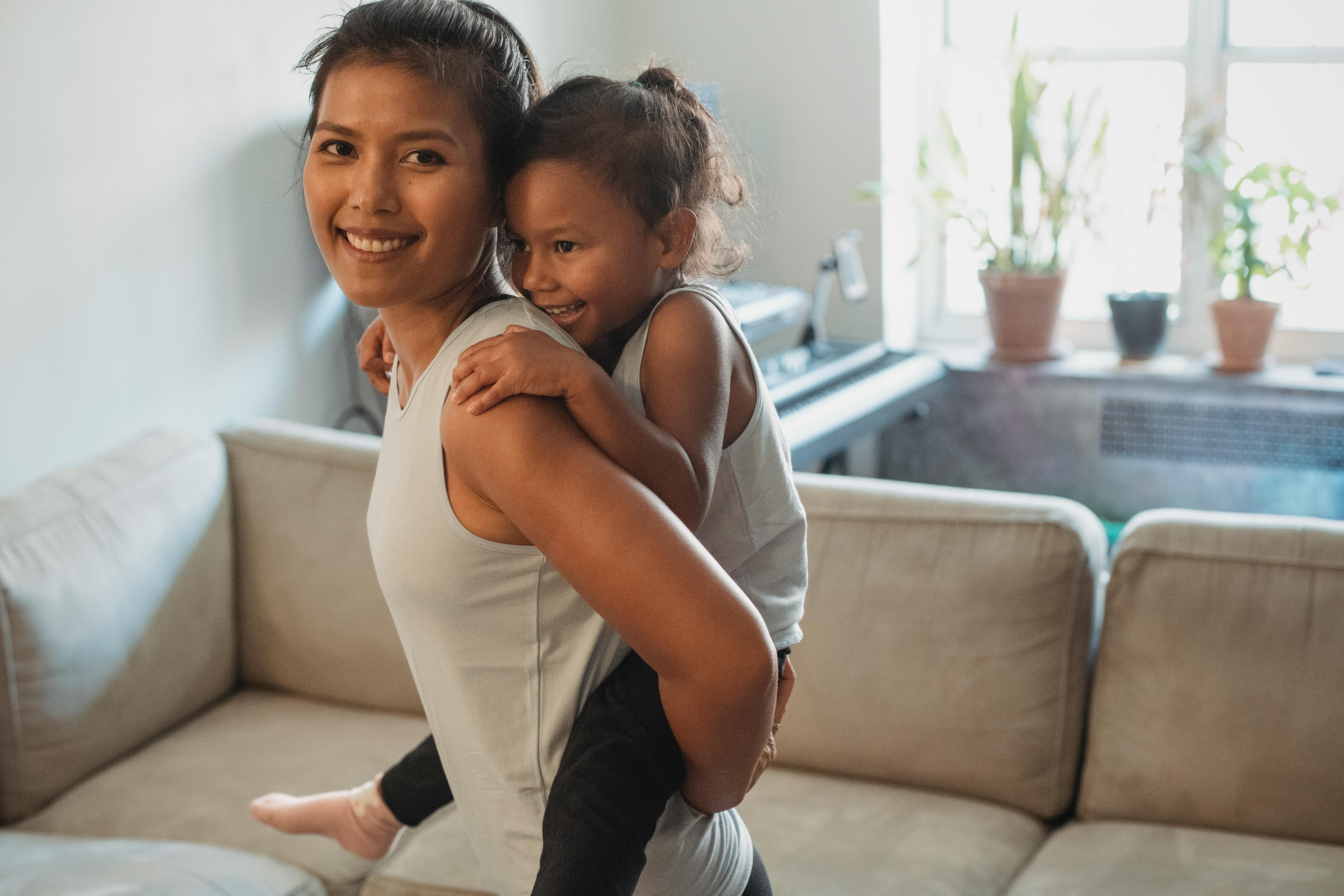 smiling mother carrying daughter on back