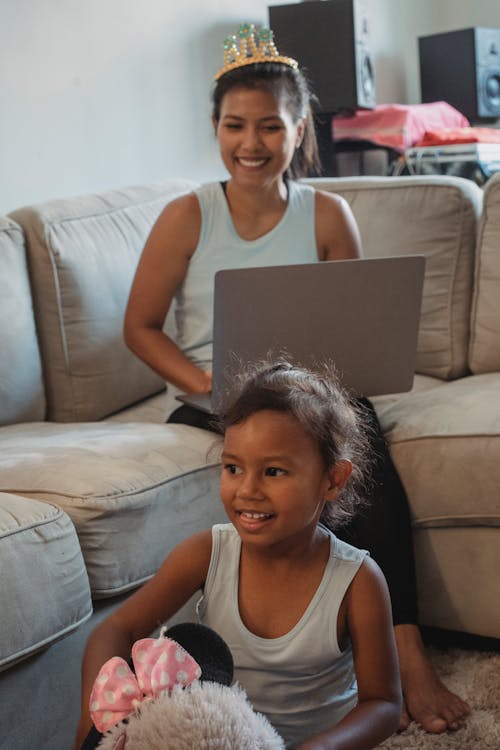 Ethnic mother with laptop looking at daughter