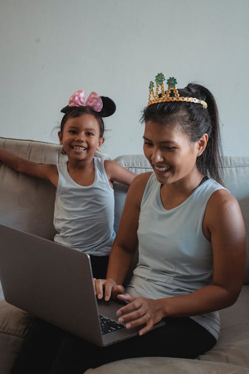 Ethnic woman using computer while kid playing