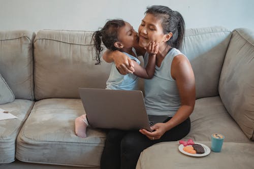 Free Hispanic mother and daughter hugging on couch Stock Photo