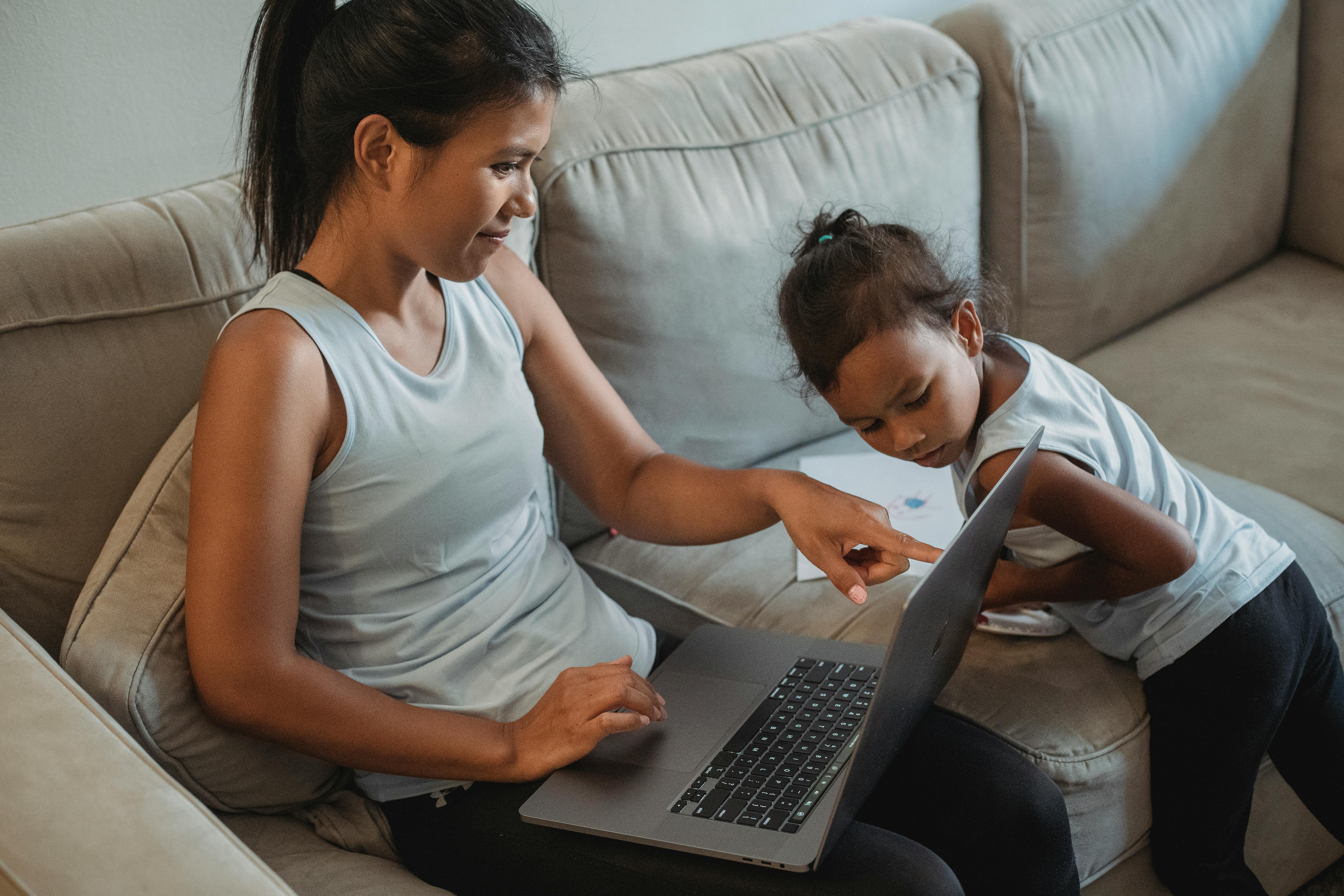 hispanic female with child watching computer on sofa