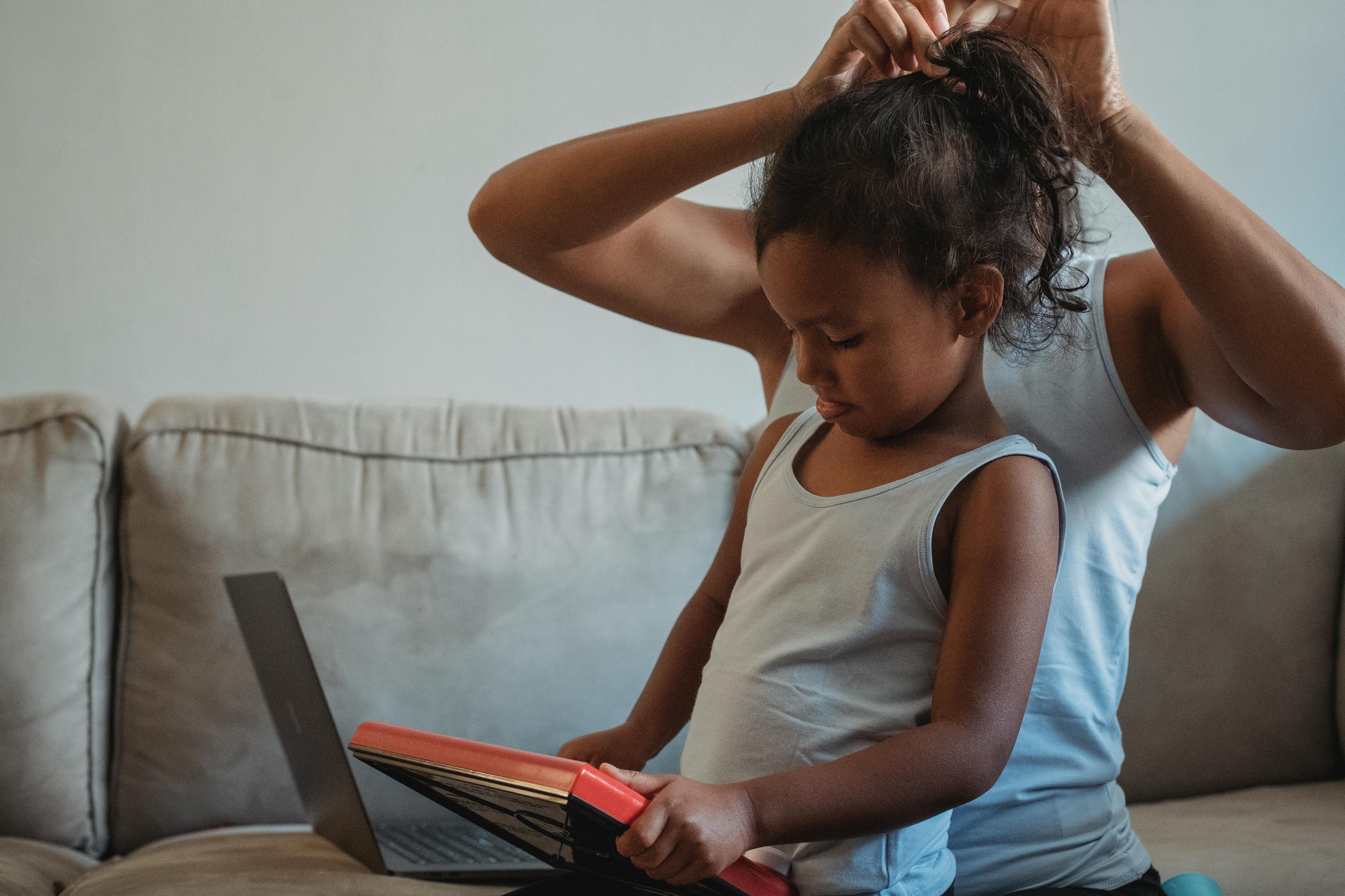 woman changing child hairstyle in living room