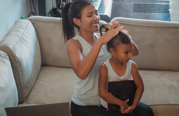 Smiling Mother Braiding Daughter Hair At Home