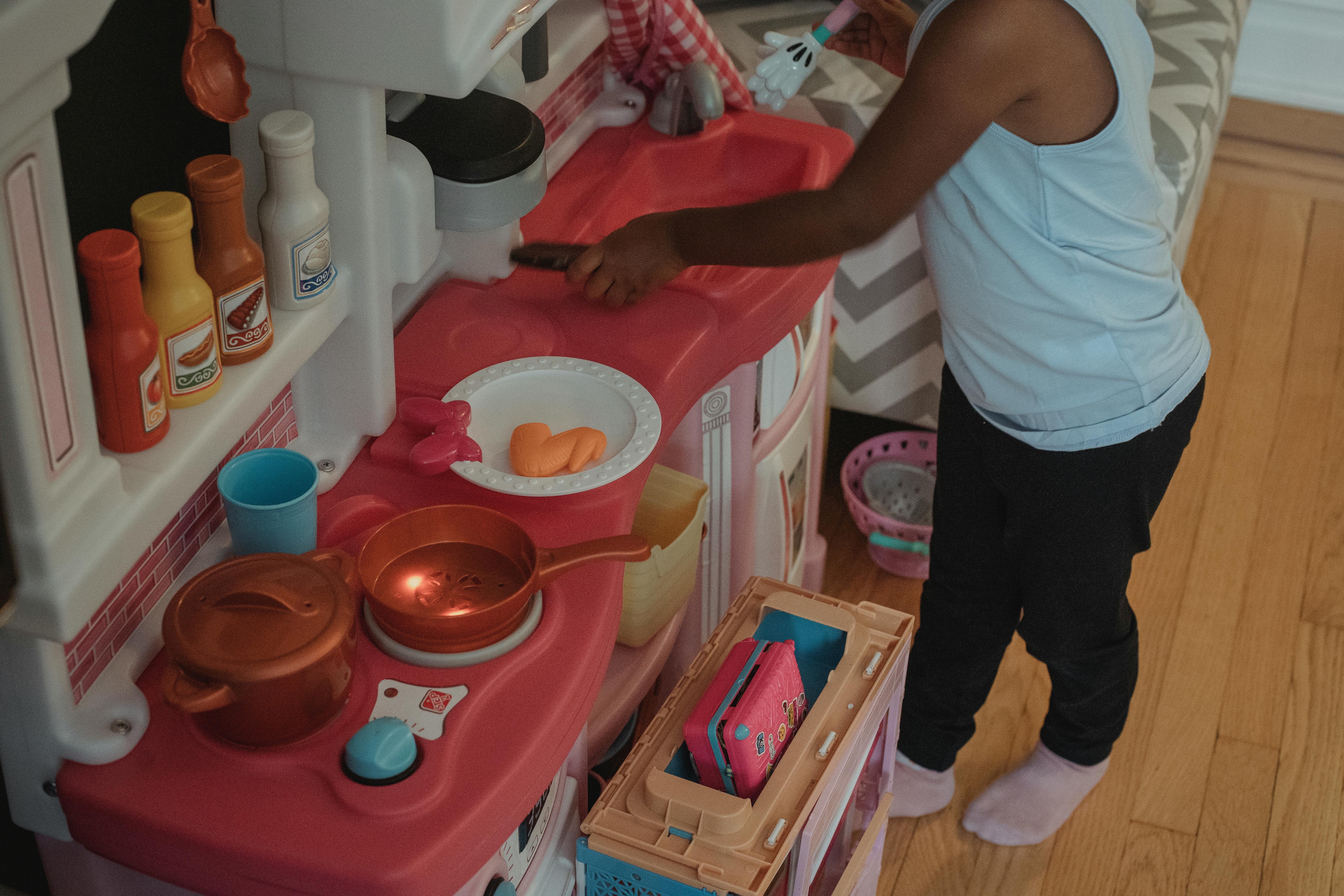 faceless kid playing on toy kitchen