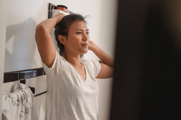 Young Woman Brushing Hair In Bathroom