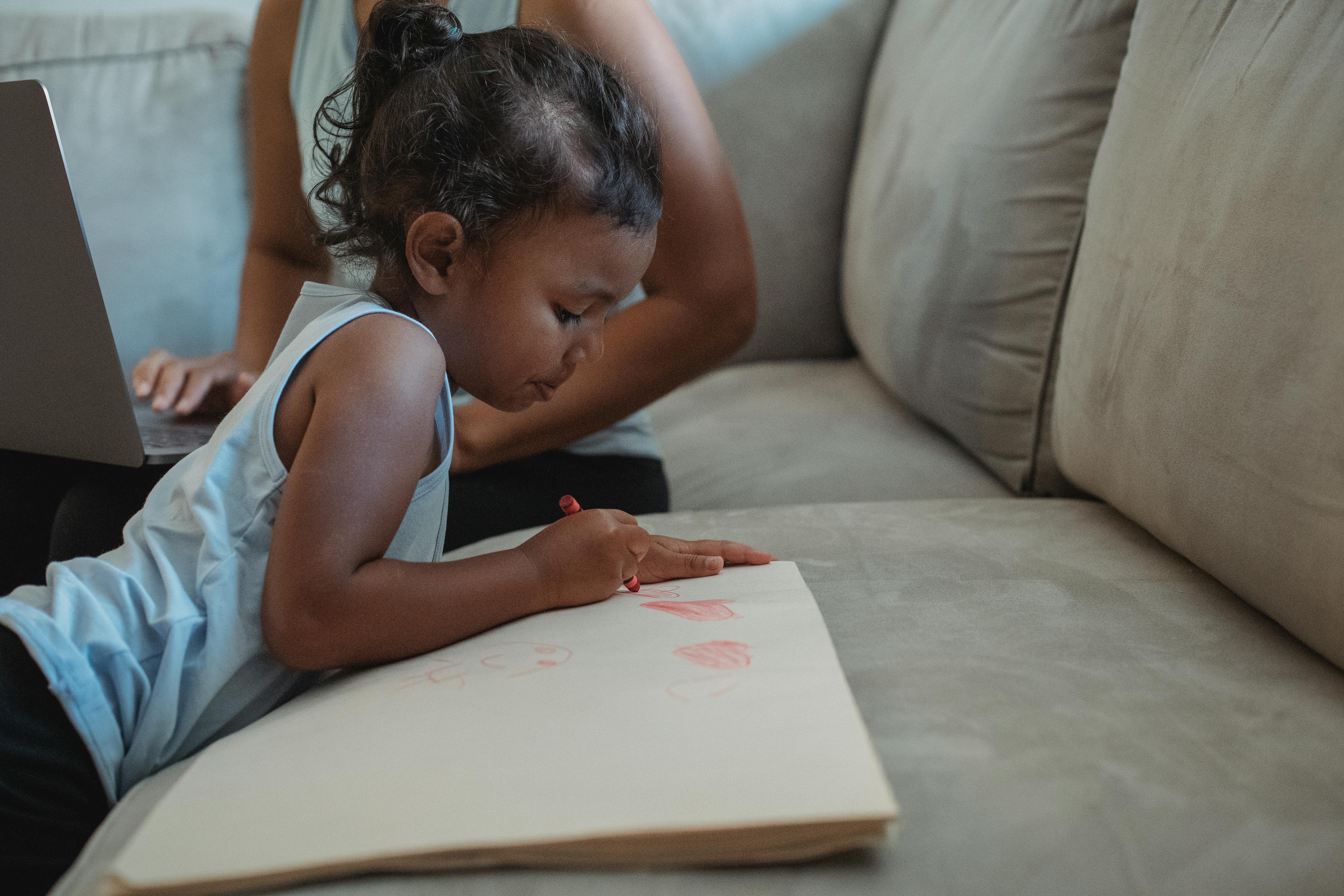 concentrated ethnic girl drawing on paper