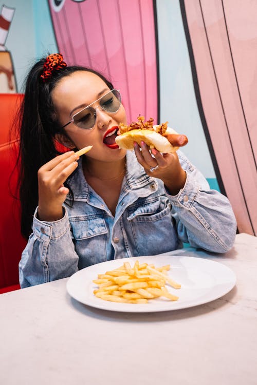 Wanita Dengan Jaket Kancing Denim Biru, Makan Makanan