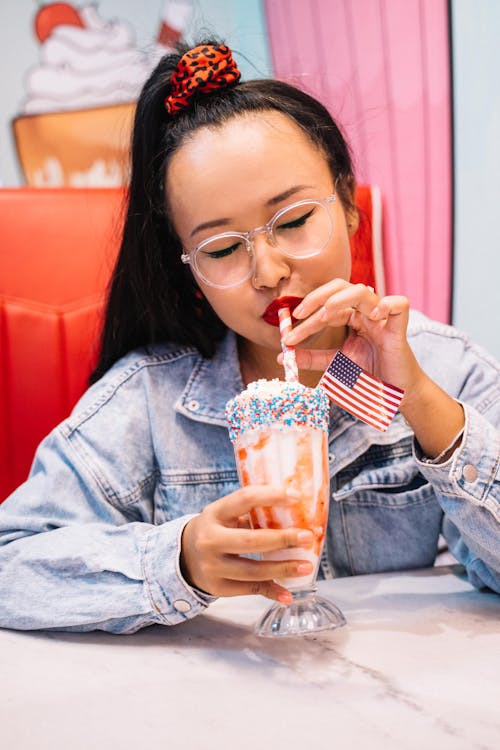 Wanita Dengan Jaket Denim Biru Minum Dari Kaca Minuman Bening