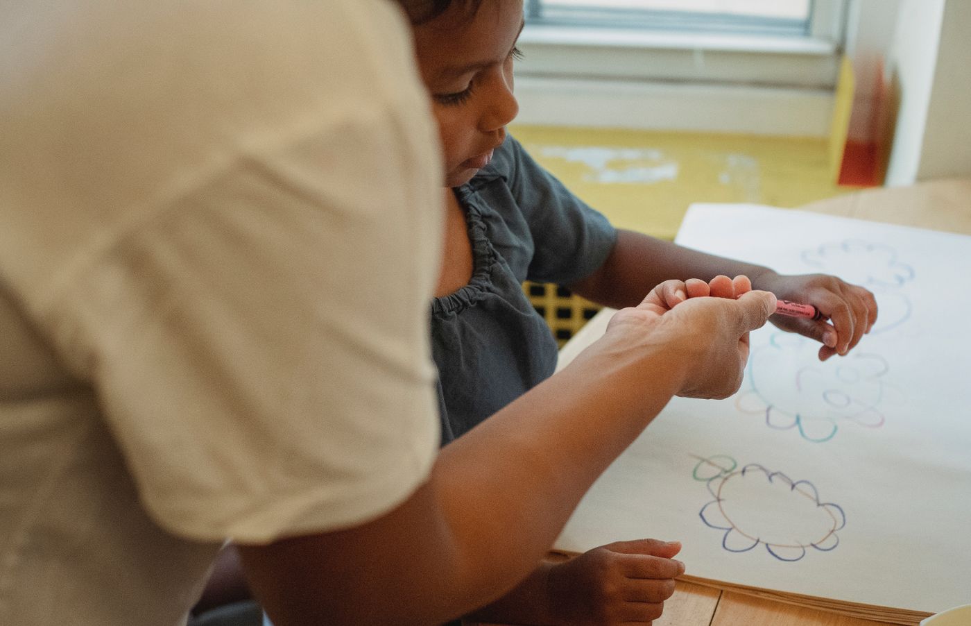 Close-up of a mother and child drawing together with colourful crayons.