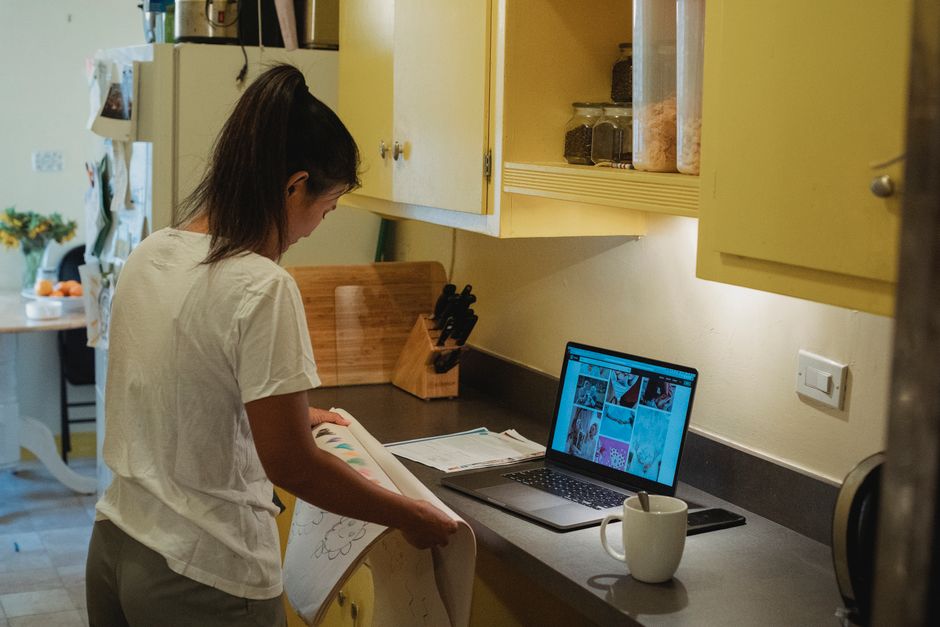 All-Clad D5 vs Tramontina Tri-Ply: Durability and Heat Distribution Showdown Side view of young Asian female in comfy clothes standing at table with laptop and checking drawings in album during remote work at home