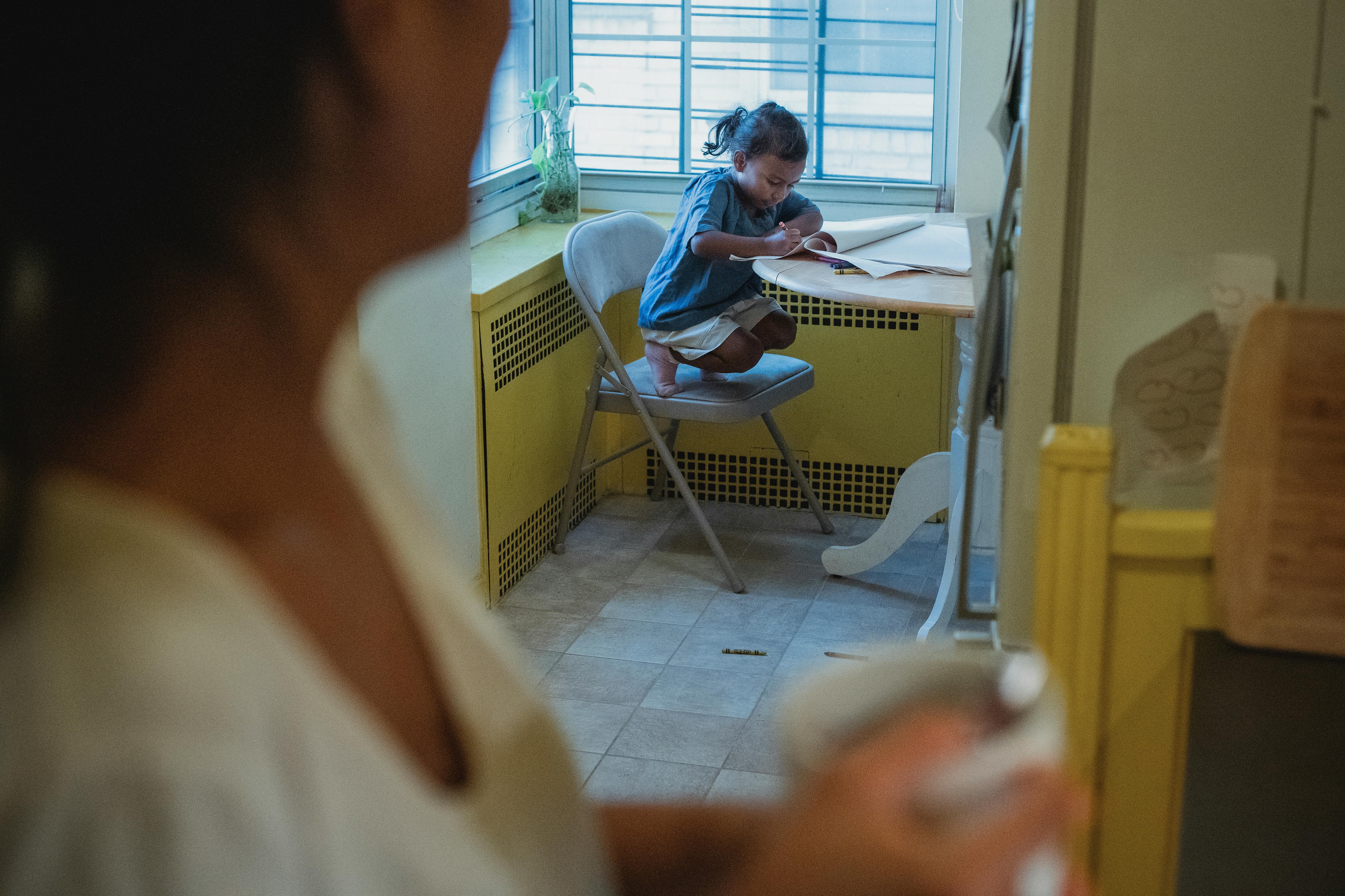 crop ethnic woman with cup in kitchen with daughter