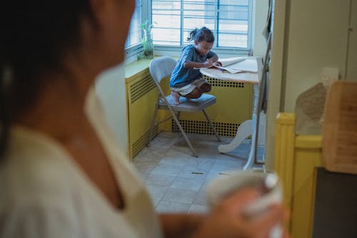 Pangkas Wanita Etnik Dengan Cangkir Di Dapur Bersama Anak Perempuannya