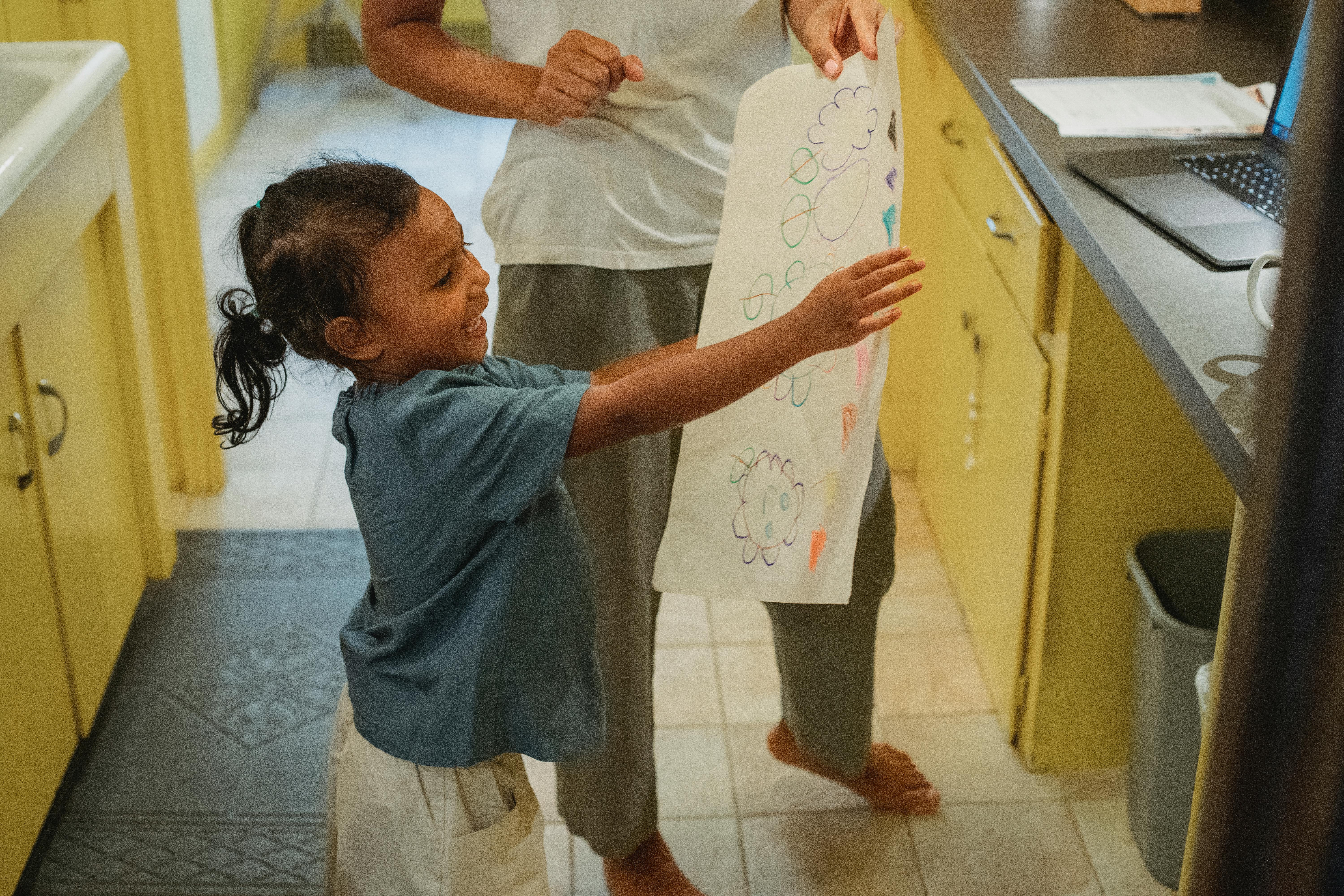 cheerful asian daughter showing drawing to crop mother