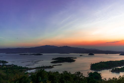 Picturesque scenery of peaceful sea with small islands and with hills against bright sunset sky