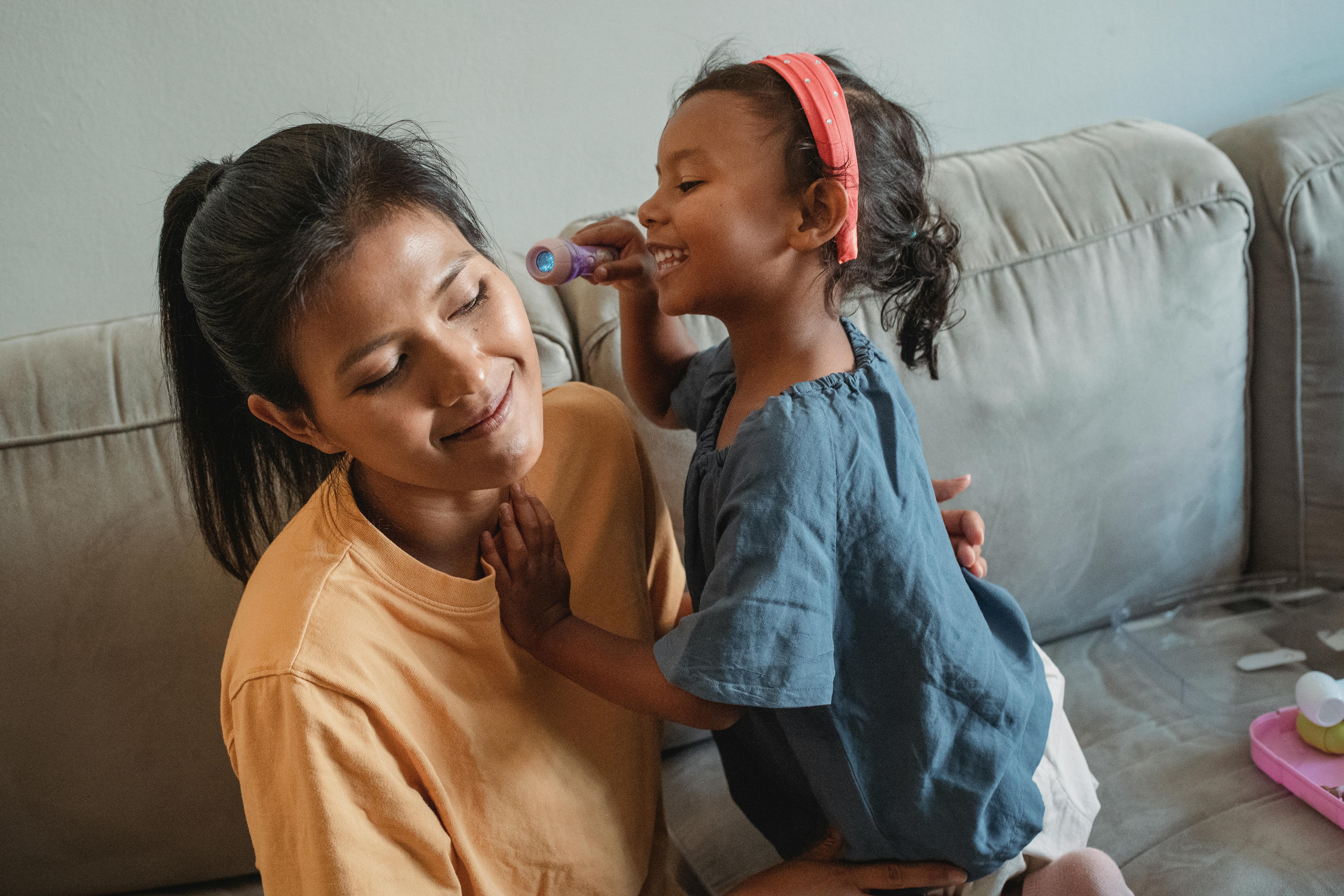 ethnic daughter with flashlight playing with mother