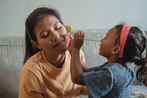 Asian mother with closed eyes playing with daughter in apartment