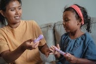 一位母亲和她的女儿在沙发上高兴地玩着假装医生与玩具注射器的游戏