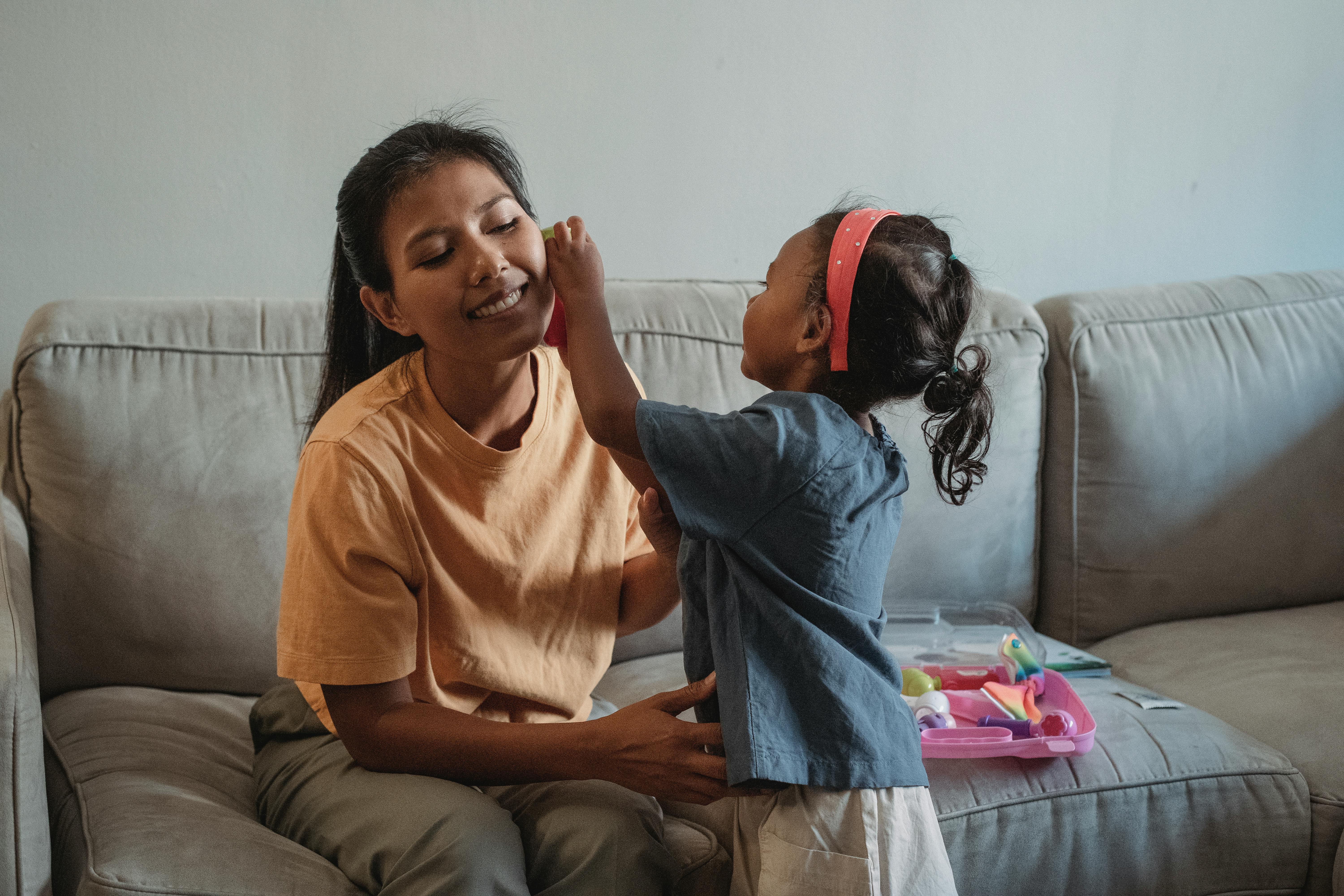 asian daughter doing examination of happy mother while playing doctor