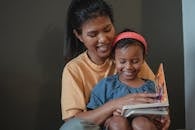 Positive Asian mother and daughter reading tale