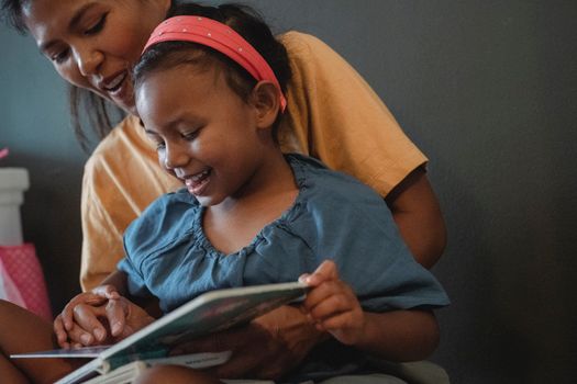 Positive crop Asian mother with daughter reading book
