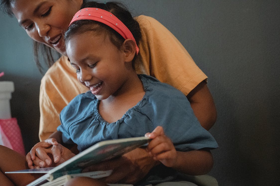 Free Positive crop Asian mother with daughter reading book Stock Photo