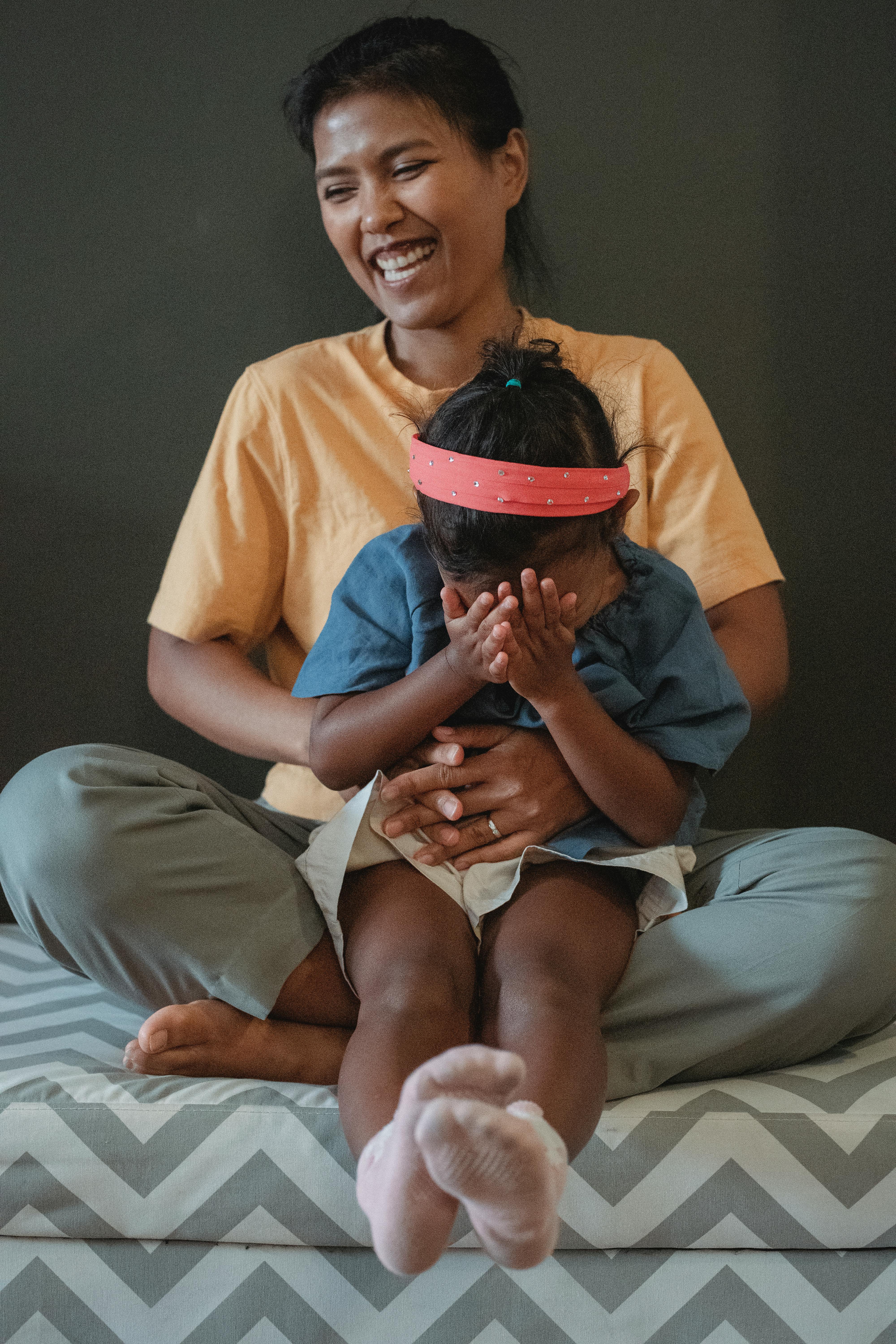 happy asian mother and daughter sitting on sofa