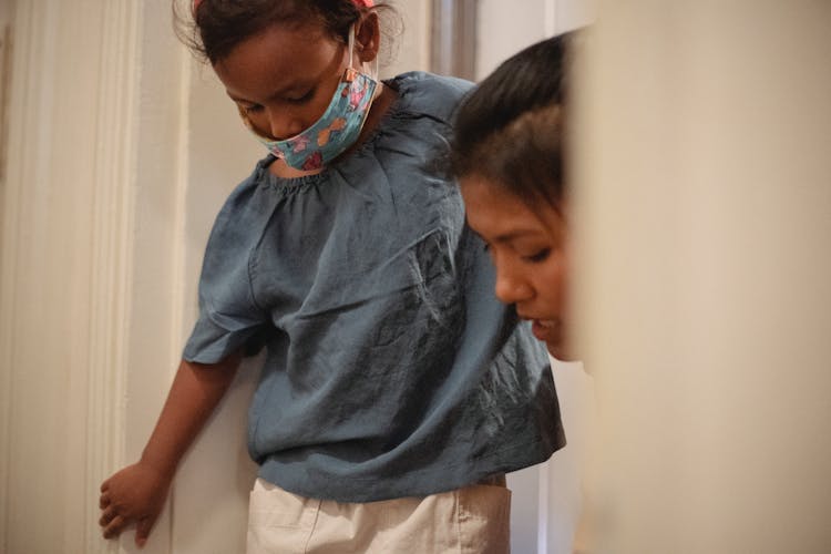 Crop Asian Woman Helping Daughter To Put On Shoes