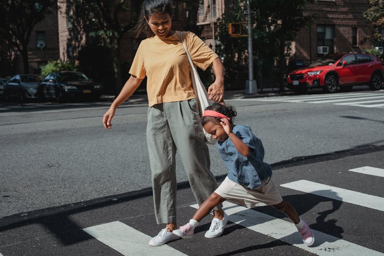 Playful Asian Mother And Daughter Crossing Road