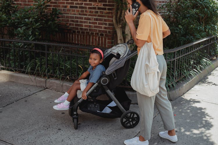 Ethnic Mother And Daughter Walking On Street