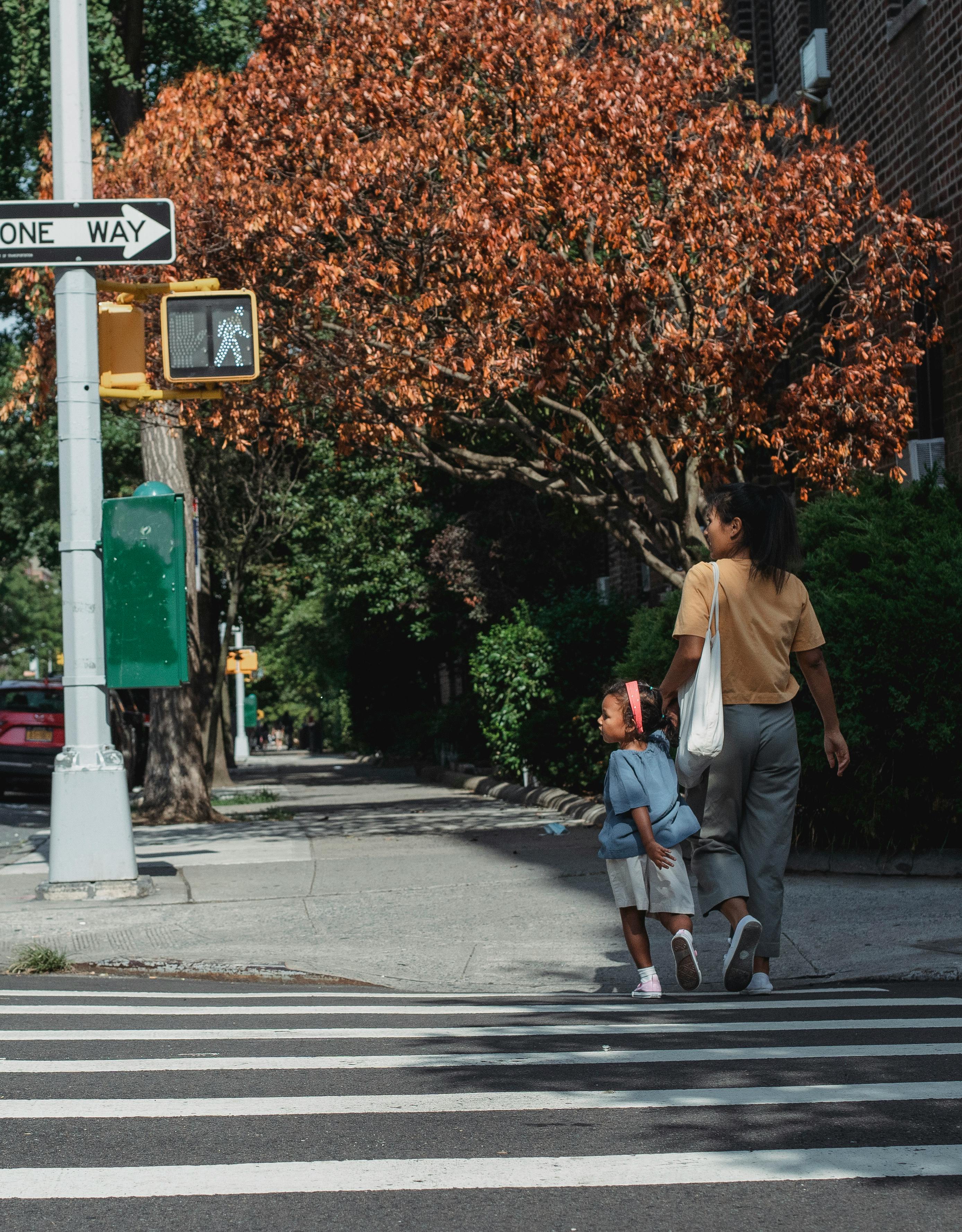 unrecognizable ethnic woman and girl crossing road