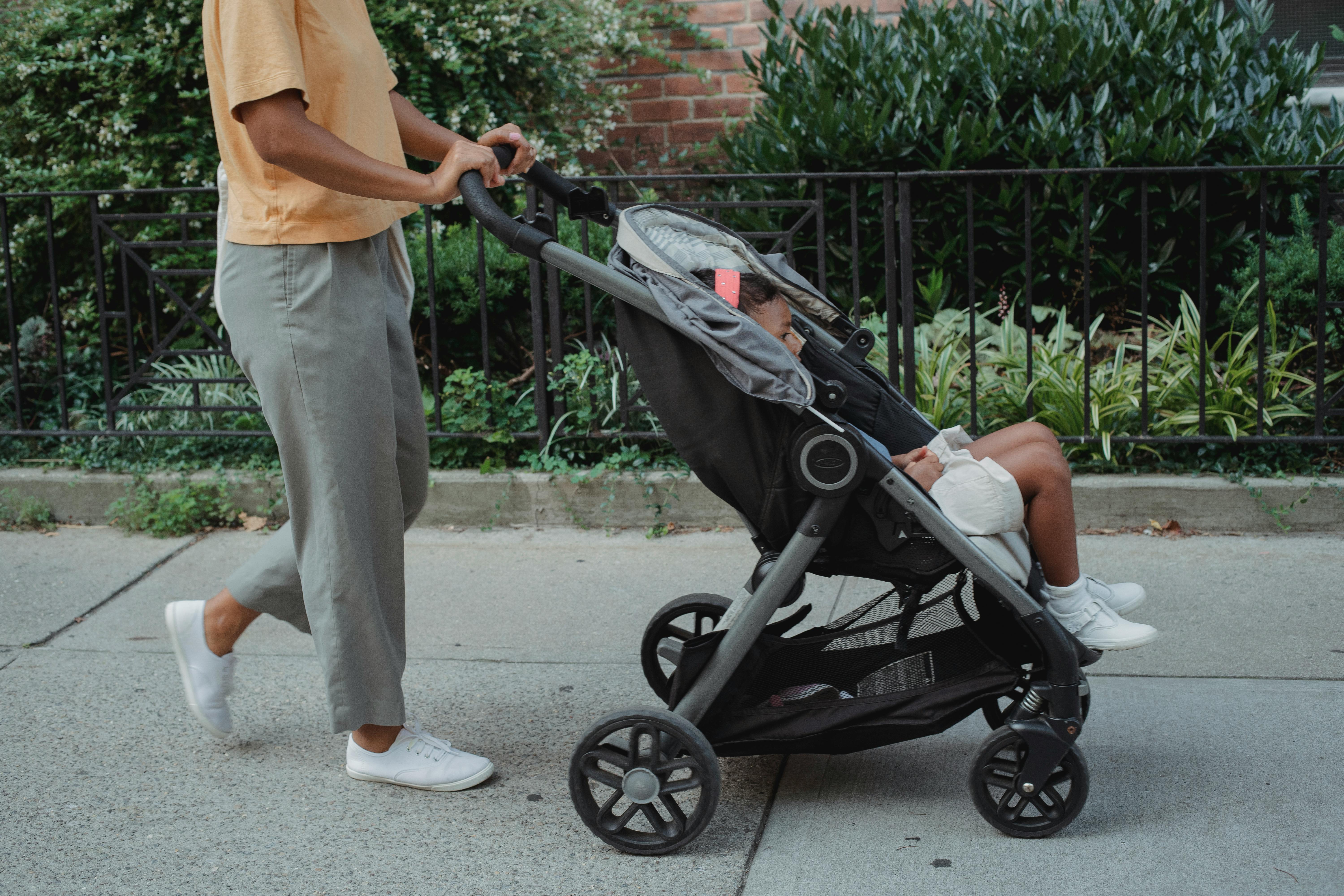 Crop woman walking with child in stroller