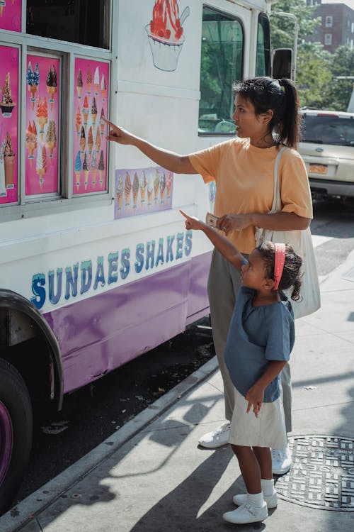 Asian mother with daughter pointing at signboard with ice cream