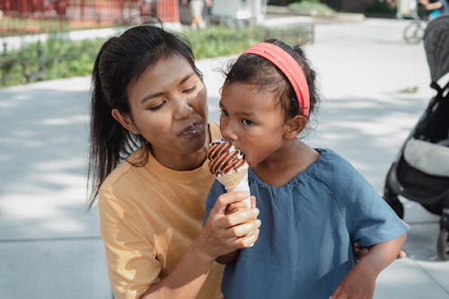 Free Happy ethnic mother feeding daughter with tasty sweet ice cream Stock Photo