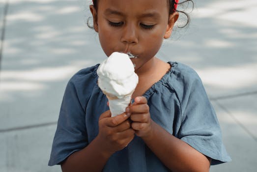 A young girl savoring an ice cream cone on a sunny day.