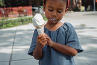 Asian girl with dirty mouth eating ice cream on street