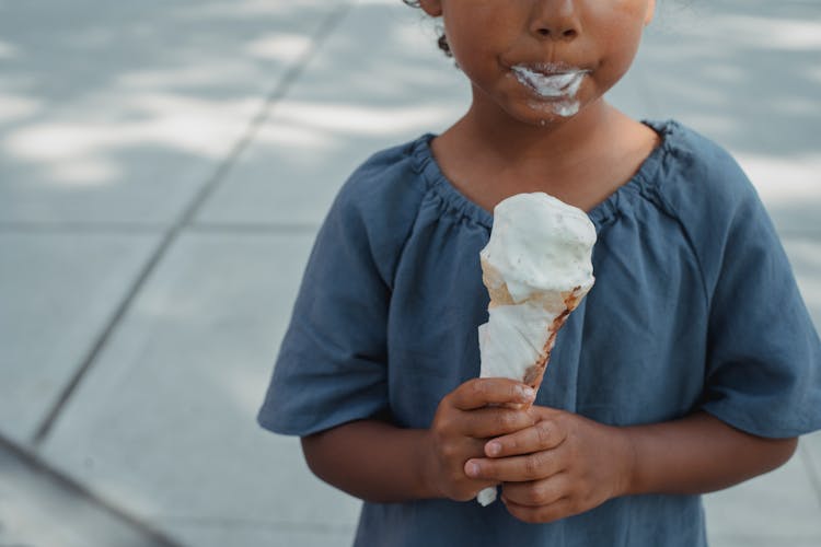Little Child With Dirty Mouth Standing With Ice Cream On Street