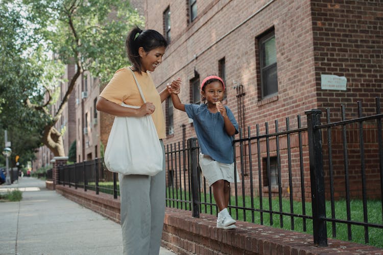 Happy Asian Mother And Daughter Walking On Street In City In Daylight