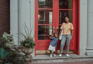 Cheerful Asian mother and daughter standing near entrance of house