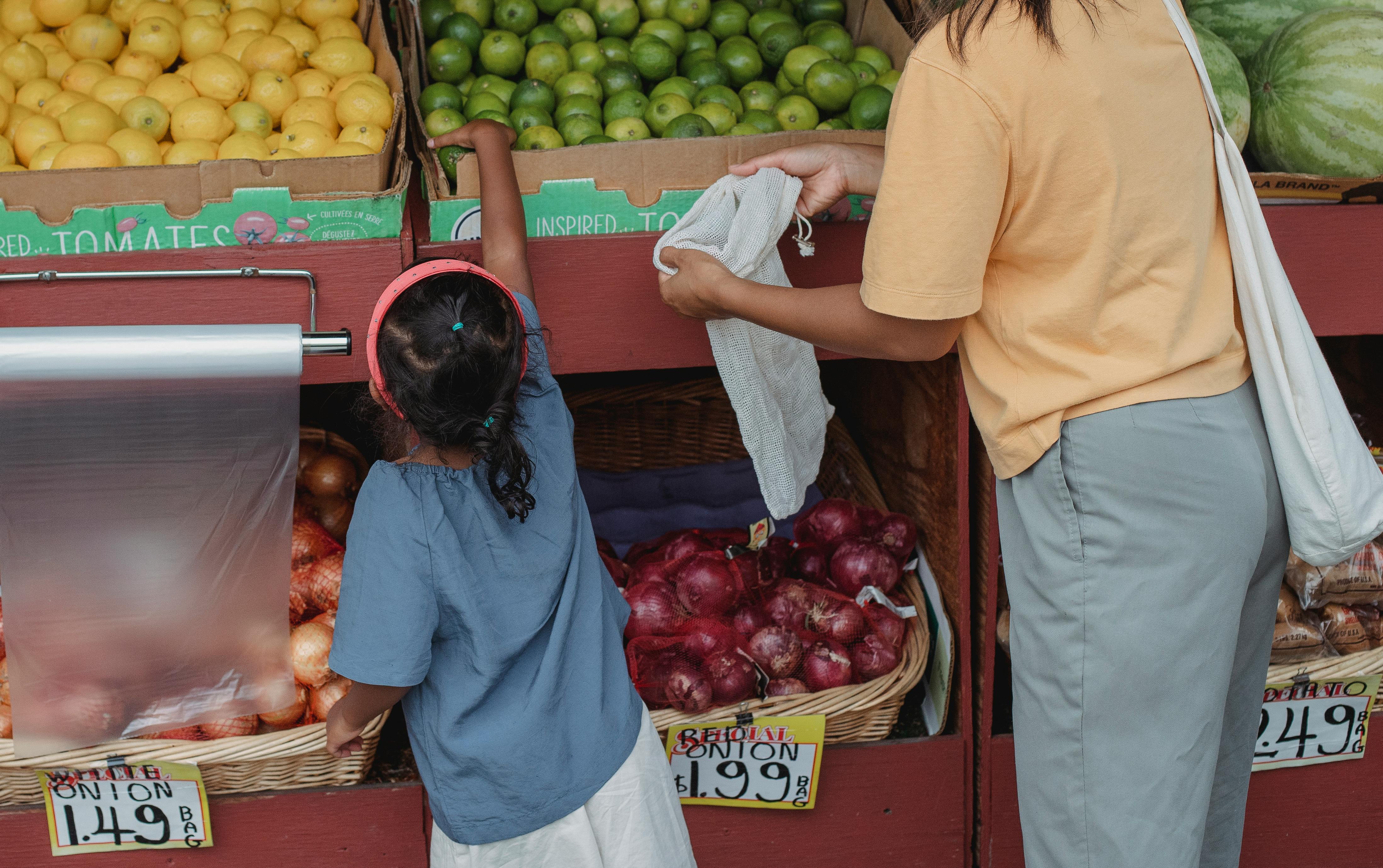 ethnic woman with daughter picking limes in market