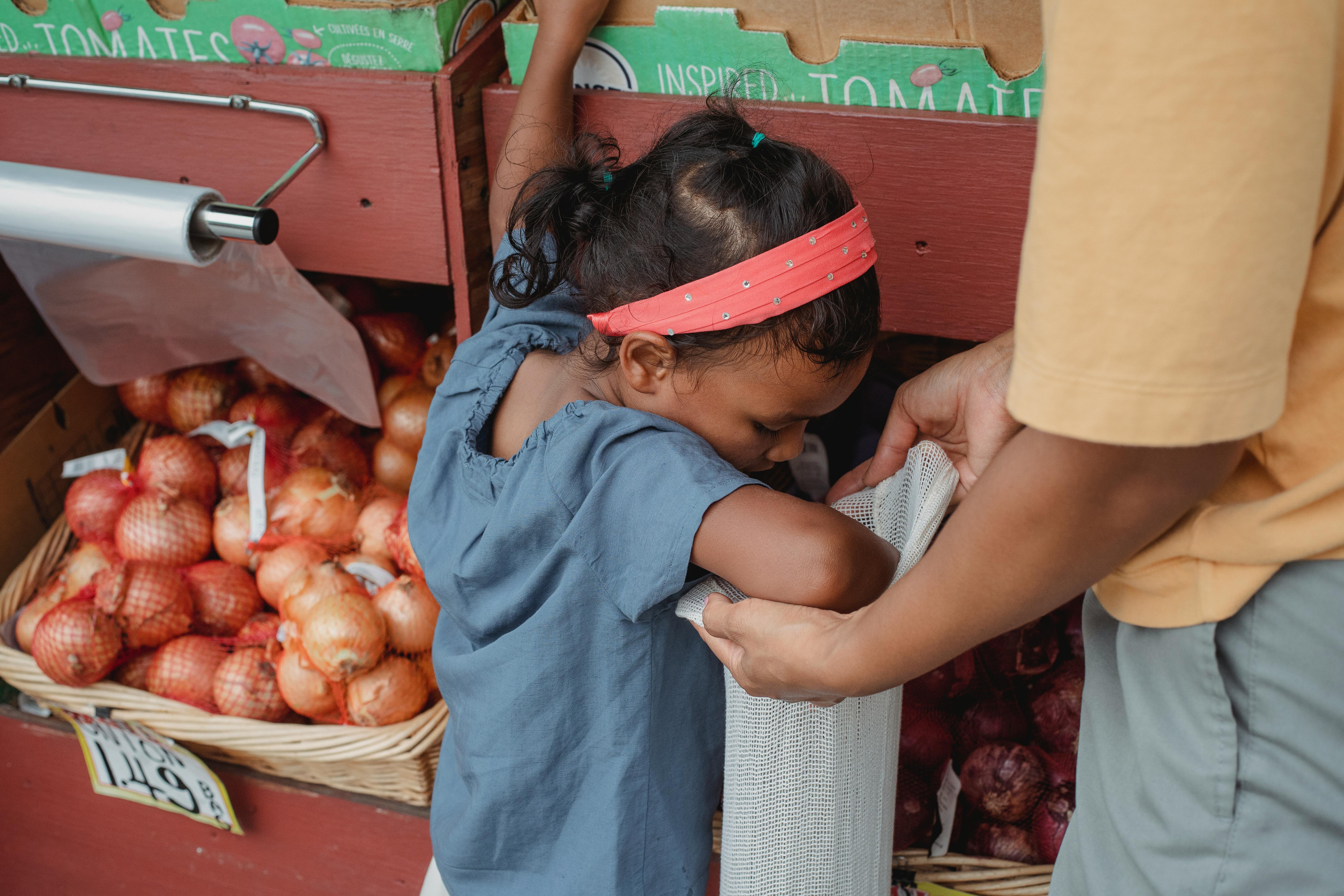 asian girl buying vegetables with mother in local street market