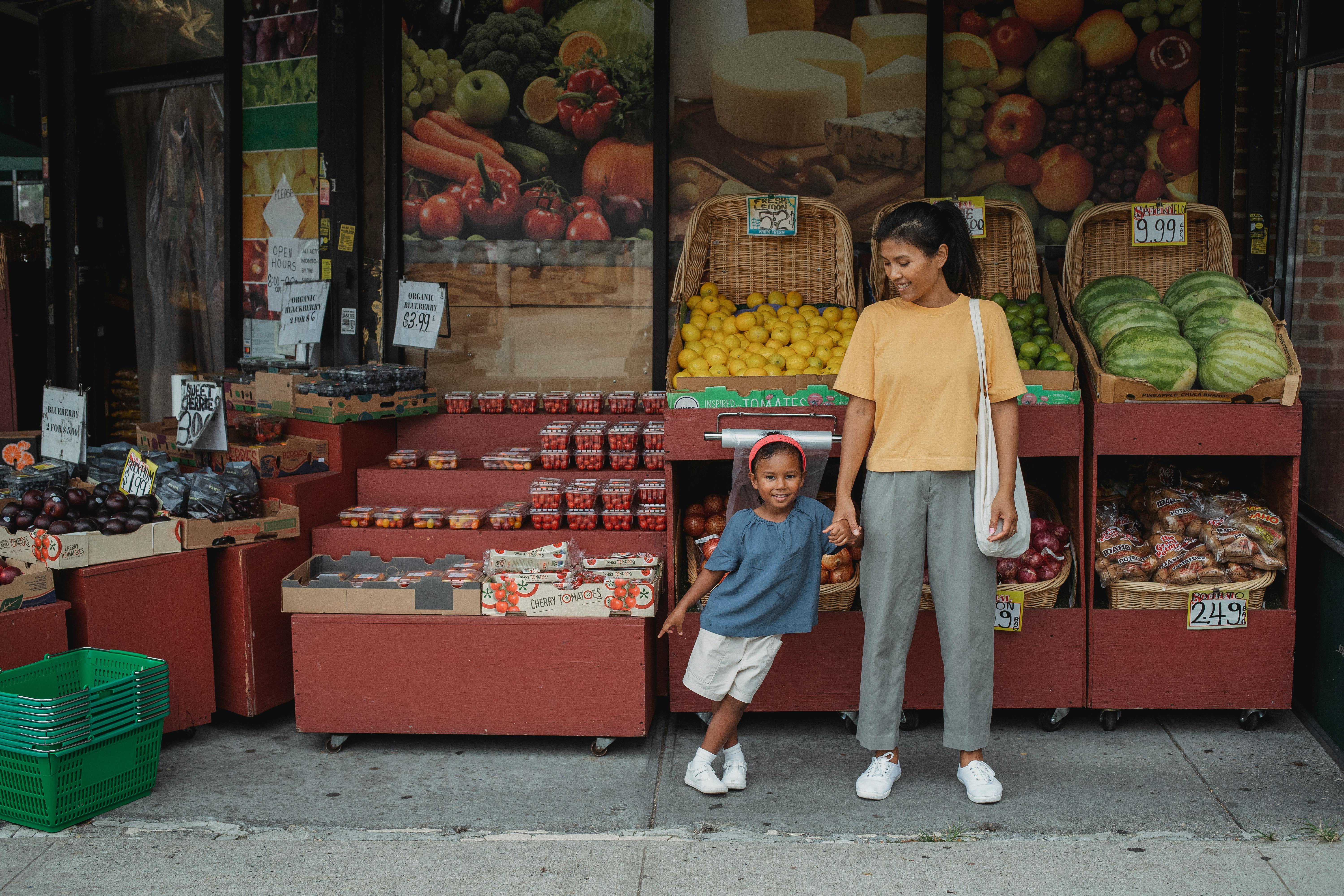 happy asian mother and daughter standing near street market stall