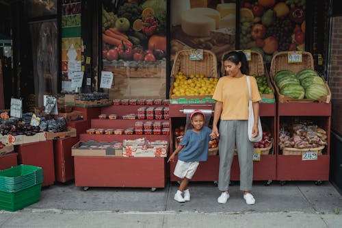 Happy Asian mother and daughter standing near street market stall