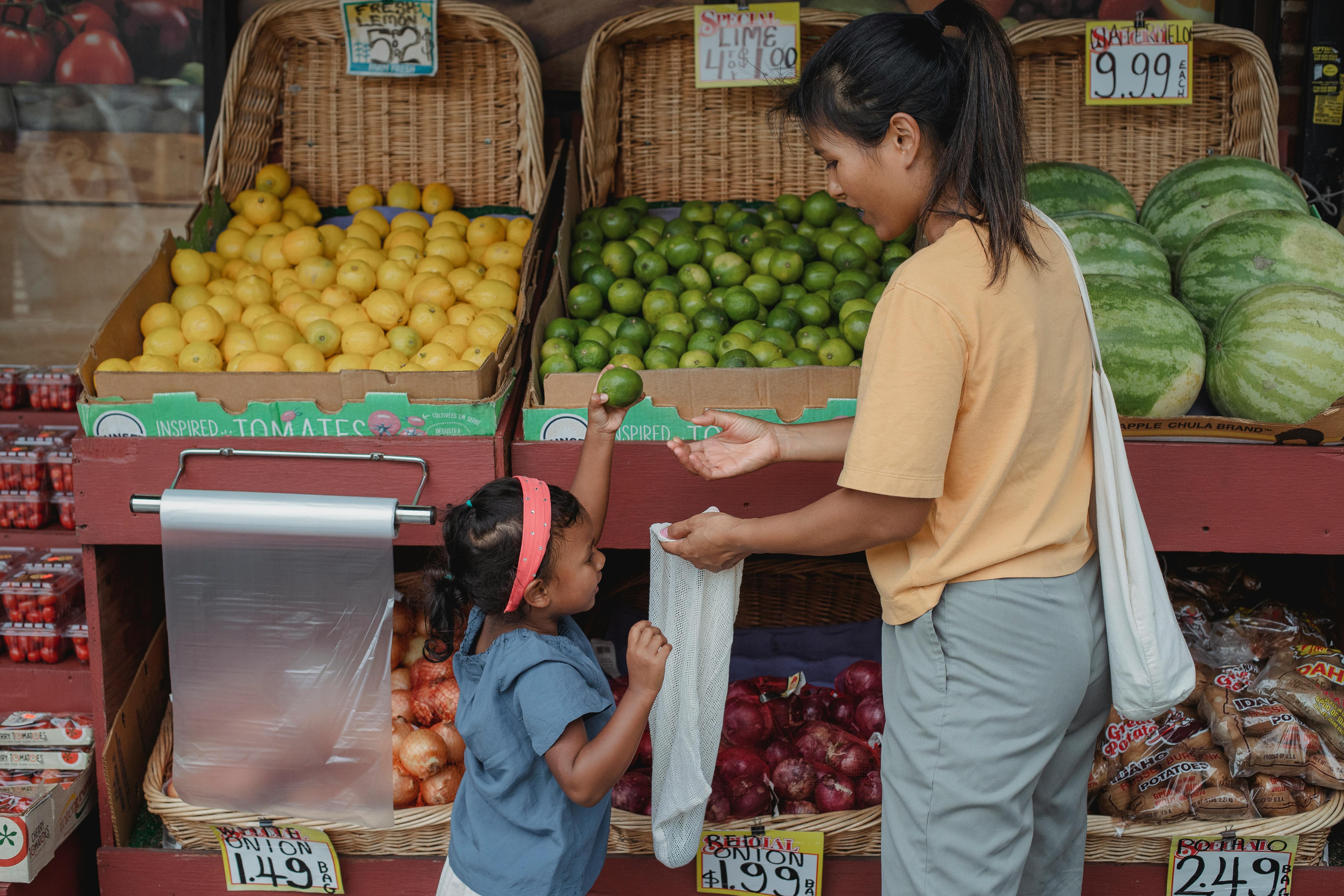 content asian mother and daughter choosing fruits in street market