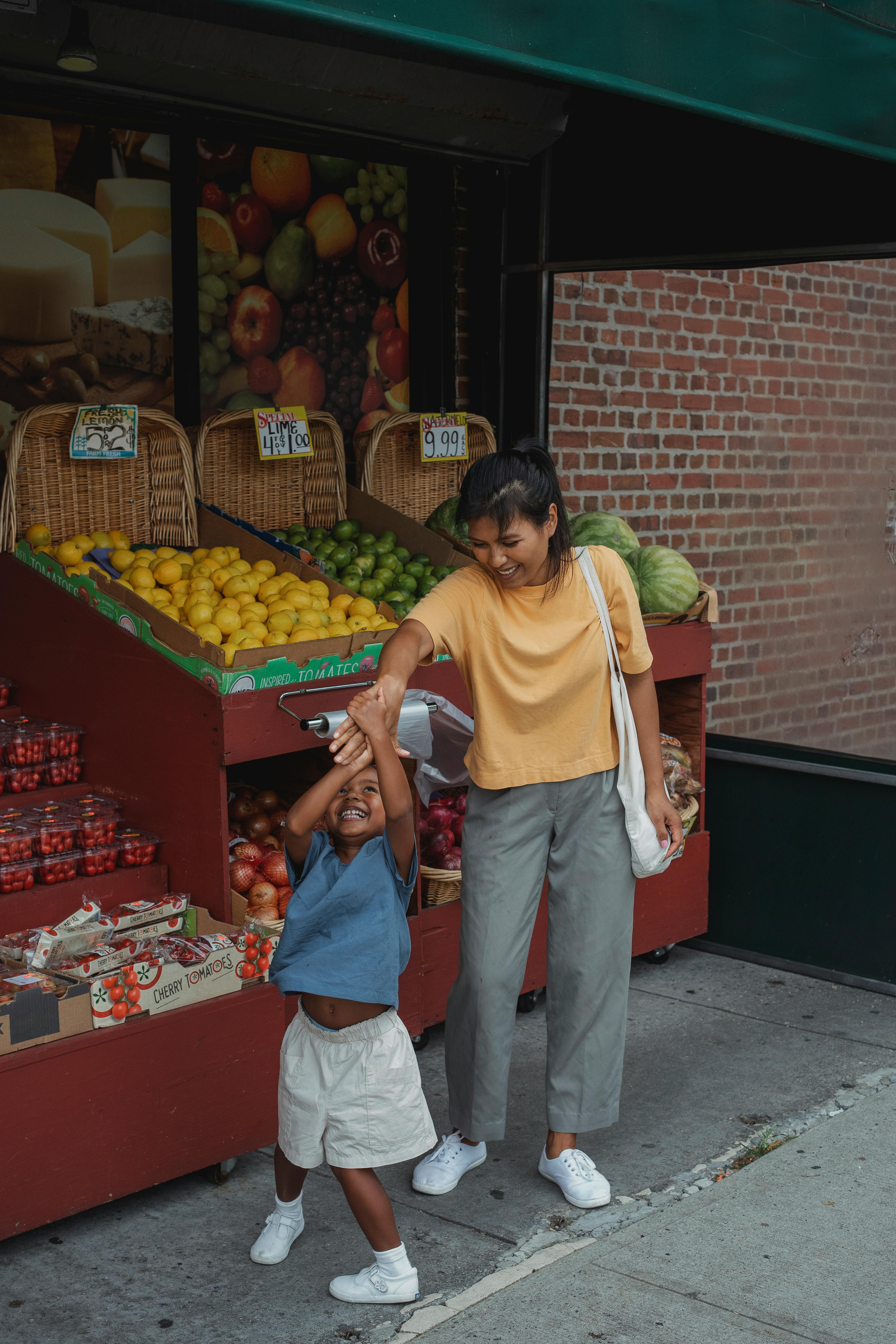 cheerful asian mother and daughter playing in street market