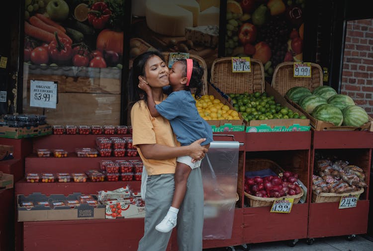 Asian Girl Kissing Mothers Cheek In Street Food Market