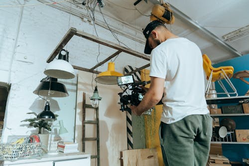 Man in White Crew Neck T-shirt and Gray Pants Holding Black and Yellow Power Tool